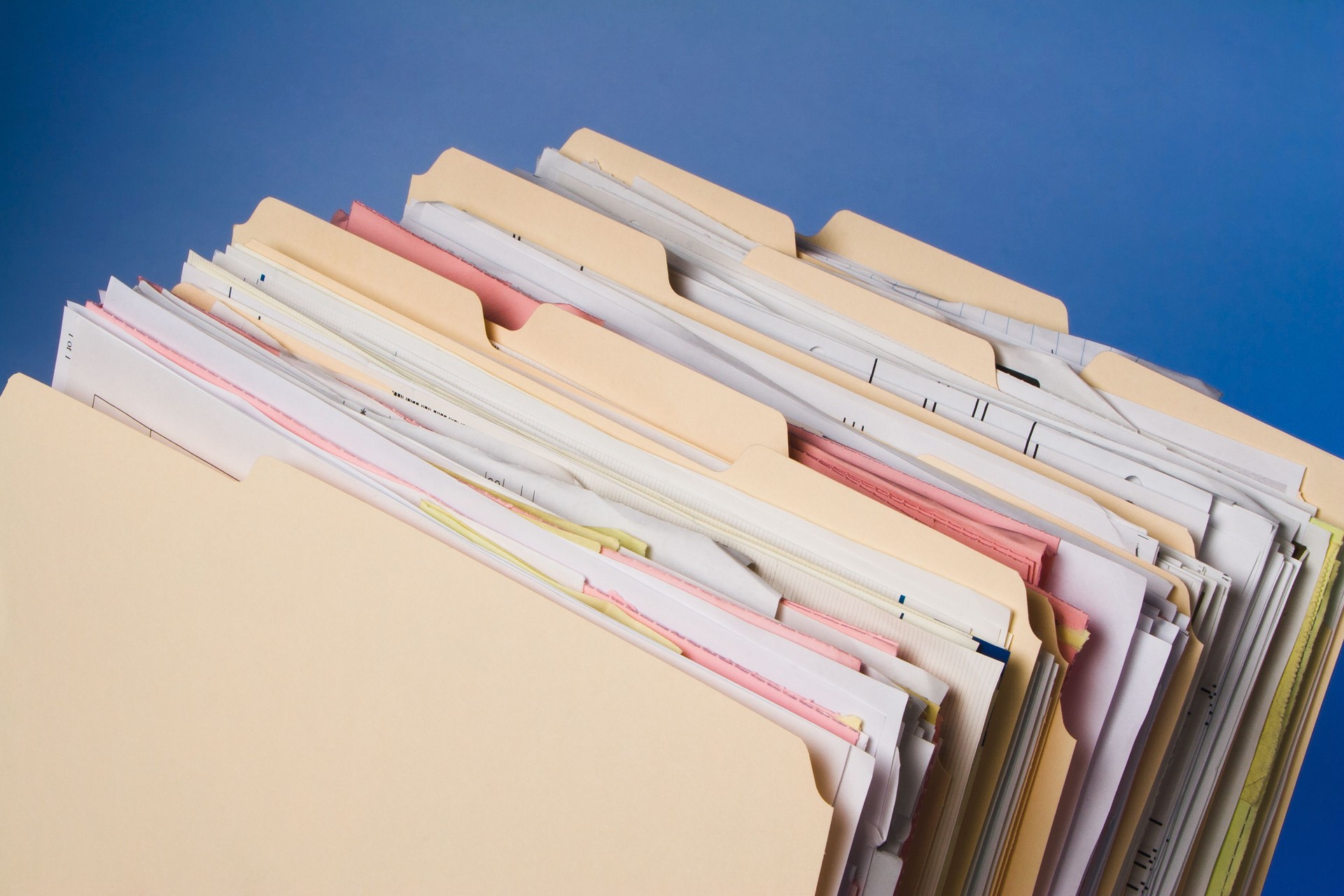 Group of full Manila folders in rack on blue background